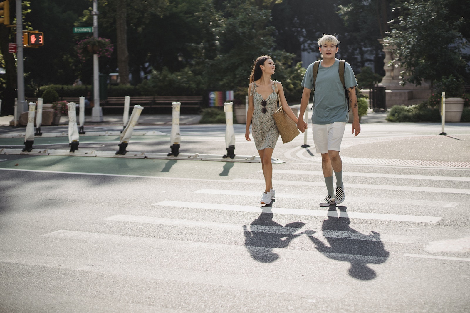 Young stylish diverse couple holding hands while walking on crosswalk