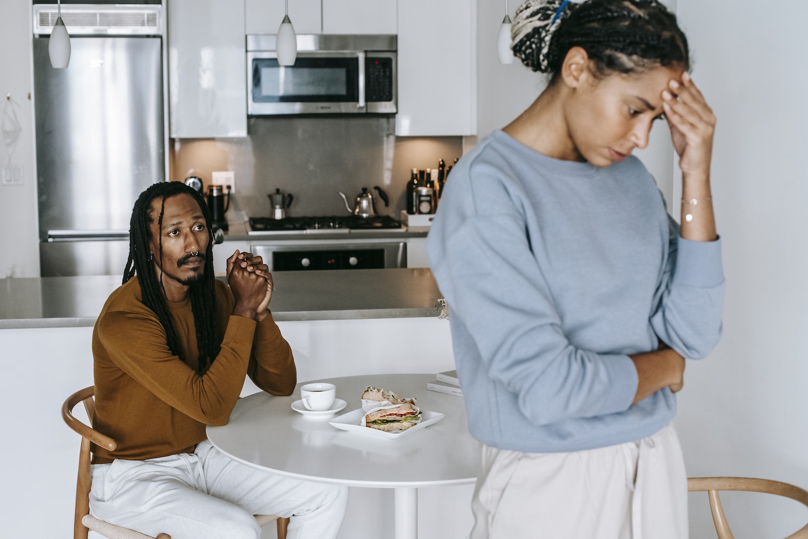 Young African American man sitting at table and arguing with woman while having breakfast at home
